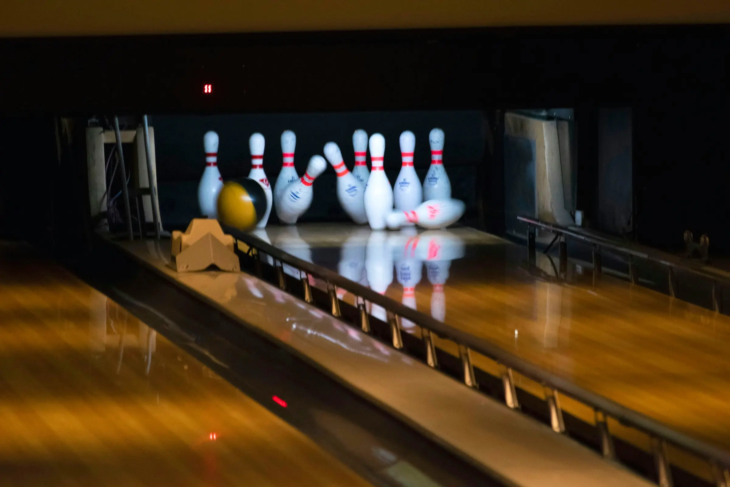 Bowling ball hitting the pins at the end of a polished wood lane